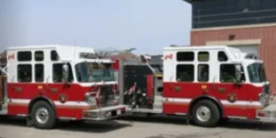 two red fire trucks parked outside of a fire station