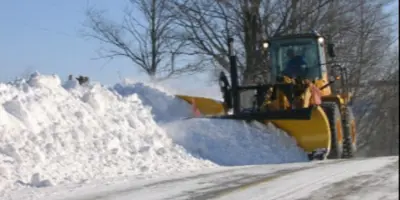 yellow plow pushing a snow pile