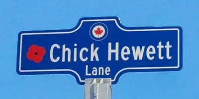 Blue street sign for Chick Hewett Lane with red poppy