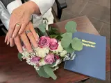Couples hands with rings, over Marriage Register book
