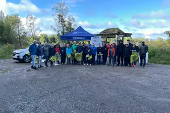 group photo of people with garbage bags in front of tents