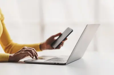 Hands on laptop with mobile phone